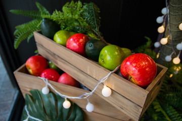 Red and green apple on a wooden box with light decoration.