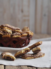 Homemade sandwich puff pastry chocolate cookies in a wicker natural plate from the vine. Wooden ancient table. View from above.