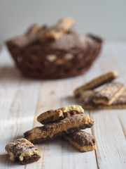 Homemade sandwich puff pastry chocolate cookies in a wicker natural basket of vines. Wooden ancient table.