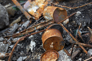 Corroded and rusty metallic components - can, and tin.  Ash, dust and dirt around destructed and ruined objects. Aged old abandoned waste and garbage made of iron (shallow depth of field).