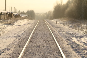 Railroad stretching into the distance a winter sunny day between the city and the forest