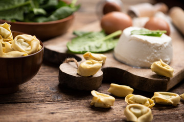 Fesh tortellini ravioli on wooden rustic table with spinach and ricotta
