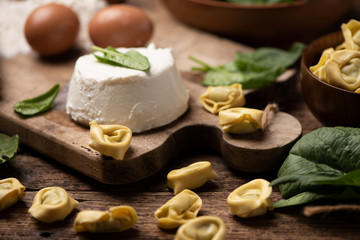 Fesh tortellini ravioli on wooden rustic table with spinach and ricotta