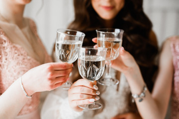 Photo bride with her friends drinking champagne from glasses