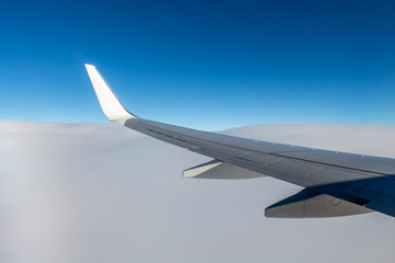 Obraz premium Plane silver wing during a flight over white clouds and a winter land is on the photo