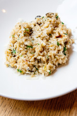 Delicious Italian vegetarian risotto cooked with mushrooms and onions served in white plate.