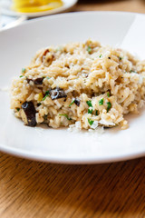 Delicious Italian vegetarian risotto cooked with mushrooms and onions served in white plate.