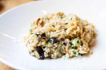 Delicious Italian vegetarian risotto cooked with mushrooms and onions served in white plate.