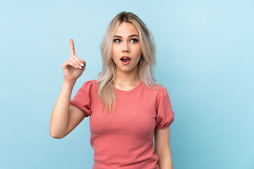 Fototapeta premium Teenager girl over isolated blue background intending to realizes the solution while lifting a finger up