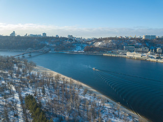 Obraz premium Aerial drone view. A ship floats along the Dnieper River in a snowy morning.