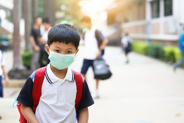 An Asian boy wearing a school uniform with a medicine healthcare mask in a school. 