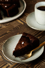 Moist Ginger Chocolate cake sliced and sprinkled with sea salt and cup of tea on wooden table. Selective focus