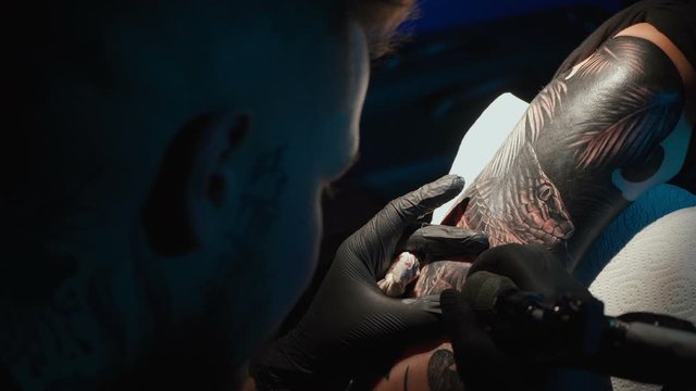 Close up video of doing black tattoo of snake for woman in studio