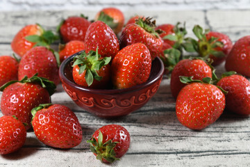 Red strawberries in a bowl on a wooden table