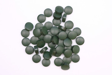 Green round pills top view on a white background. Spirulina tablets, useful dietary supplements.