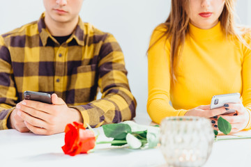 Cropped shot of boy and girl, sitting together, concentrated on their cellphones.