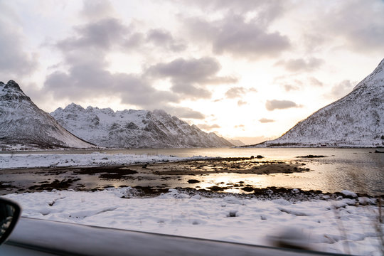 Winter road trip photo with sunset over a fjord with mountains. Lofoten islands, Norway.