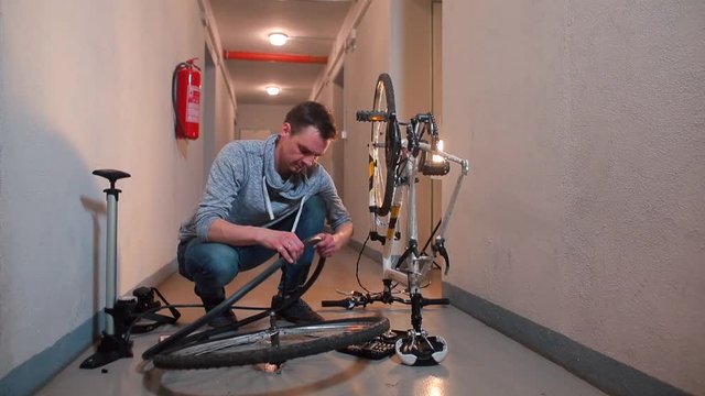 A man in a garage disassembles a bicycle wheel.