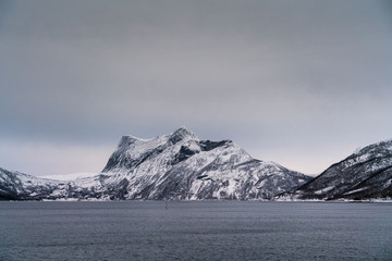 Cloudy day in northern Norway. Nature landscape of snowy mountain and a fjord.