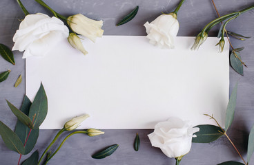 Blank paper copy space. Frame with flowers. Silk ribbon. Gray background. Simple bouquet. Greeting card.