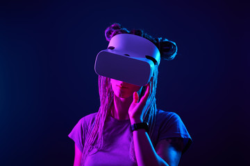 Woman is using virtual reality headset. Neon light studio portrait.