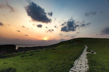 Naklejka na ściany i meble A road to the sunset beside the cliff