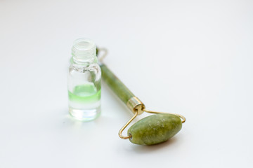 face massager and perfume on a white background