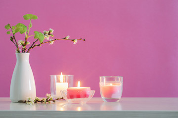 spring cherry flowers and candles on pink background