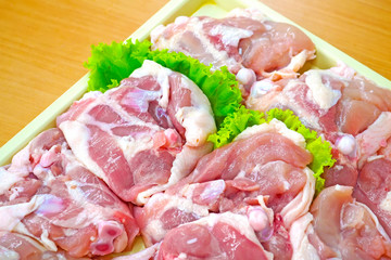 Chicken Thigh with Bone. Raw chicken thigh with fresh vegetable on tray and wood table background. Fresh Chicken Thighs meat with herbs ready for cooking.