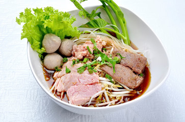 Rice noodle soup with beef ball and stewed beef and sprouts on white table. Beef noodle with vegetable and nature ingredient. Asian food. Noodles with beef and beff balls with soup Thai style.