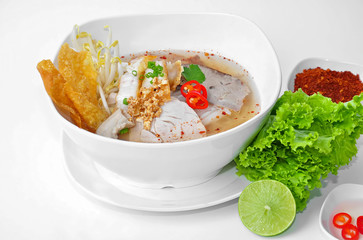 Noodle Tom Yam, noodles with pork and hot spicy soup with lemongrass, chilli paste and lime juice served with crispy noodles, taste is hot, spicy and sour with vegetable and white background.
