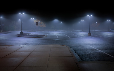 An Empty Parking Lot on a Cold, Rainy Night - with Vacant Parking Spaces and a Thick Mist Gathering Under the Lights