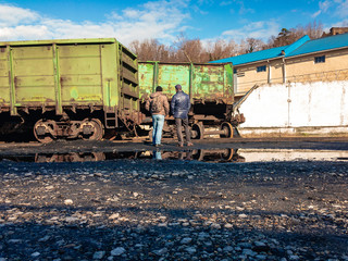  Railway accident on a sunny day. Damaged wagons after the train went off the rails and men...