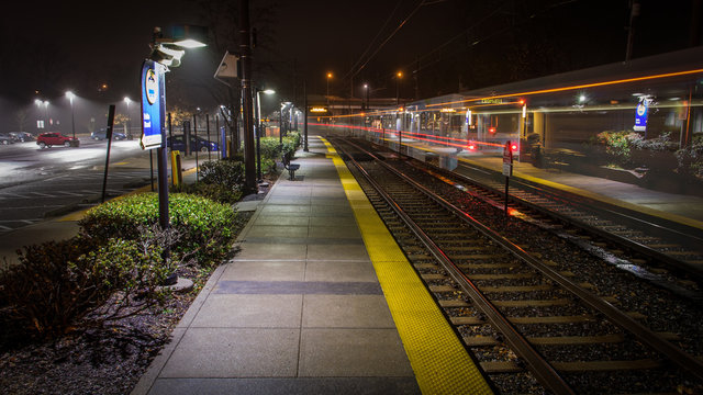 An Empty Light Rail Station in Baltimore Maryland on a Cold, Rainy Night - with Light Streaks from a Passing Train and a Thick Mist Gathering Under the Lights