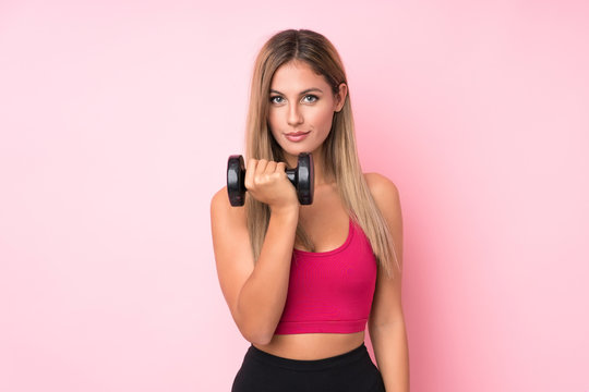 Young sport blonde woman over isolated pink background making weightlifting with kettlebell and looking to the front © luismolinero