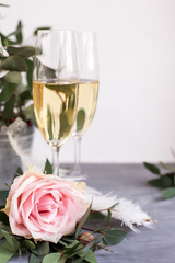 Composition with glasses of vine and flowers on grey concrete background.