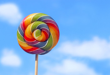 lollipop with rainbow colors in front of blue and white sky