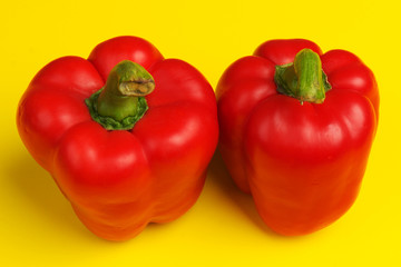 two red bell peppers on yellow background. close up