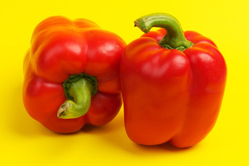 two red bell peppers on yellow background. close up