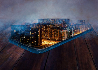a collage of a night city with clouds above it stands in an old phone lying on dark boards.