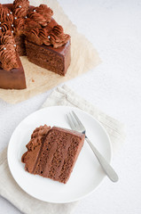 Chocolate Birthday cake. A slice of delicious chocolate cake on a light background. Piece of Cake on a white Plate. Sweet food. Sweet dessert. Vertical orientation.
