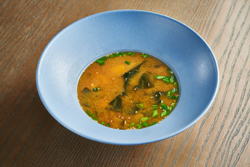 Close up view on Classic Japanese, diet miso soup with salmon, seaweed in a blue bowl on a wooden background. Tasty food photo. Film effect during post. Soft focus