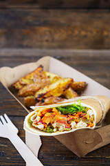 Delicious shawarma sandwich with chicken and potato on wooden background
