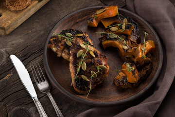 Chicken baked with pumpkin. Baked chicken with pumpkin. Roasted pumpkin and meat. Chicken pieces on a cushion of vegetables. Autumn dish. Everyday autumn kitchen. Orange colors. 