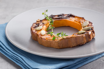 Pumpkin grill served on a plate. Baked pumpkin sliced rings with a knife, fork and napkin on a concrete table. Autumn dish. Halloween dish. Everyday autumn kitchen. Orange colors. space for text.  