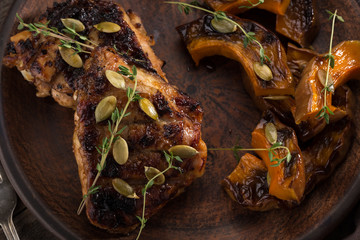 Chicken baked with pumpkin. Baked chicken with pumpkin. Roasted pumpkin and meat. Chicken pieces on a cushion of vegetables. Autumn dish. Everyday autumn kitchen. Orange colors. 