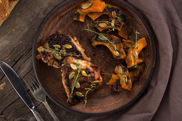 Chicken baked with pumpkin. Baked chicken with pumpkin. Roasted pumpkin and meat. Chicken pieces on a cushion of vegetables. Autumn dish. Everyday autumn kitchen. Orange colors. 