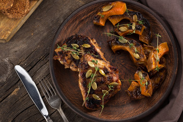 Chicken baked with pumpkin. Baked chicken with pumpkin. Roasted pumpkin and meat. Chicken pieces on a cushion of vegetables. Autumn dish. Everyday autumn kitchen. Orange colors. 