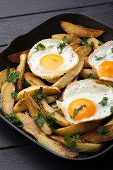 Breakfast in the pan. Fried potatoes with eggs in a skillet. Food bachelor. Cooked by a man. Hot and fresh. Homemade breakfast on black table. Fried eggs and sweet potato hash in cast iron skillet Fre