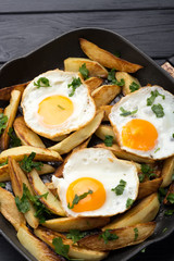 Breakfast in the pan. Fried potatoes with eggs in a skillet. Food bachelor. Cooked by a man. Hot and fresh. Homemade breakfast on black table. Fried eggs and sweet potato hash in cast iron skillet Fre